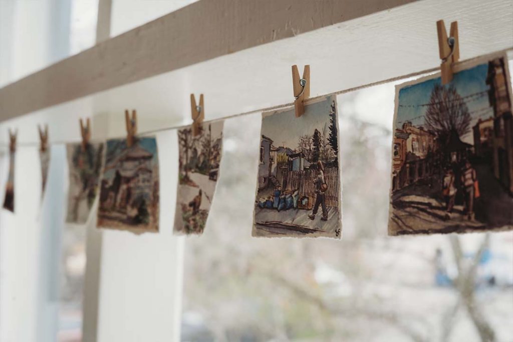 A close-up of little paintings hanging on a string in the window at the Farm Stand.