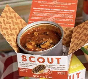 An open can of Scout mussels in a red sauce rests in a small branded Scout box.