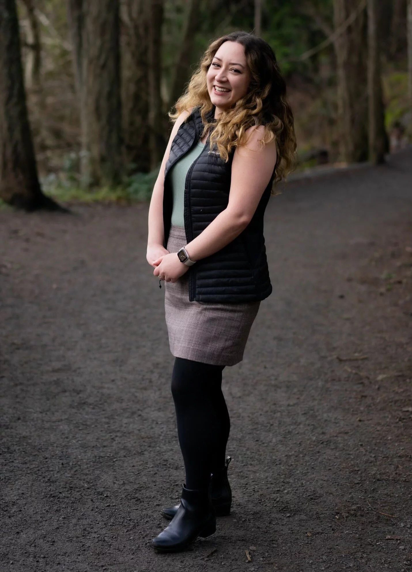 Full length photo of Carly laughing on a trail in a forest